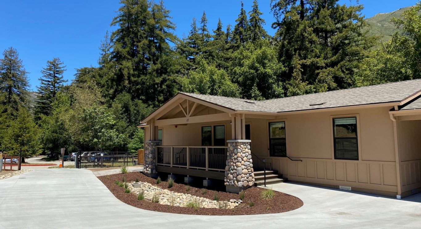 CHP government housing in Big Sur, CA. Modular construction with garage, carports, and paved driveway. Nestled in the forest.