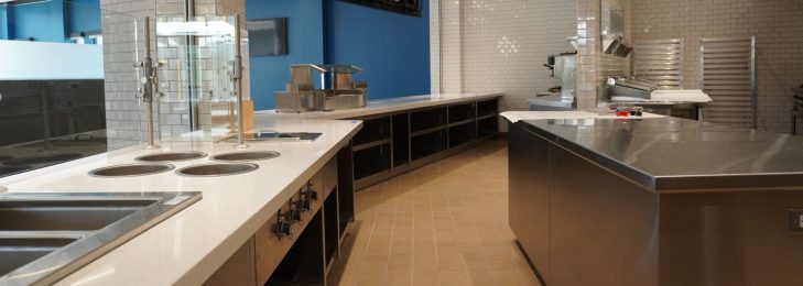 Inside of an expansive restaurant kitchen, showing stoves, ovens, and other cookware.