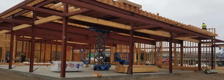 Outside of a car dealership, under construction with crew at work.